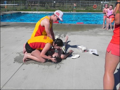 Children at the Unity swimming pool July 27 watch as lifeguards Adam Baker and Terra Fedirko perform mock CPR on drowning "victim" Logan Lindsay in a rescue demonstration during National Drowning Prevention Week. Photo by Sherri Solomko