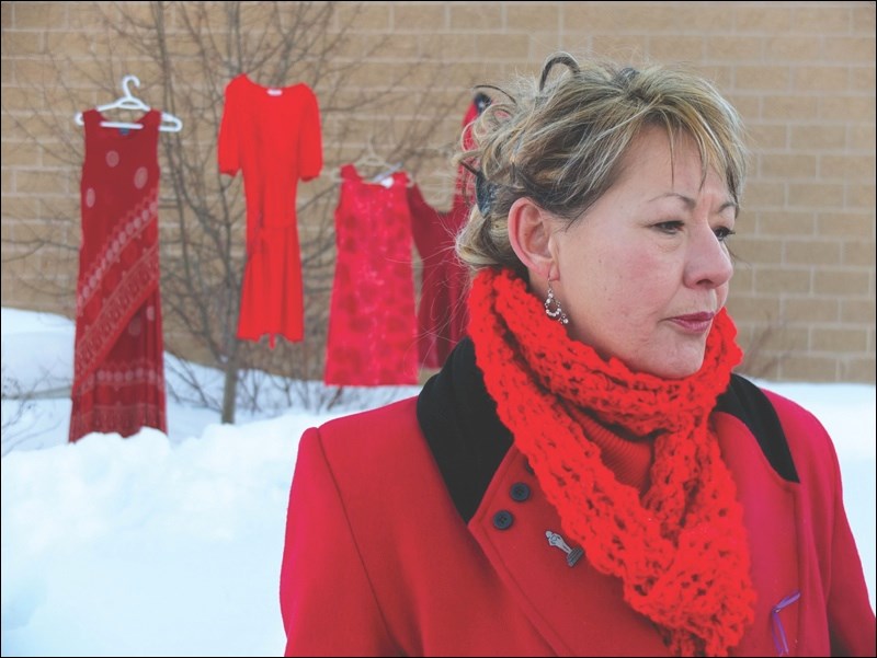 March organizer Colleen Arnold addresses participants at Pioneer Square, with four red dresses symbolizing missing or murdered aboriginal women hanging in the background.