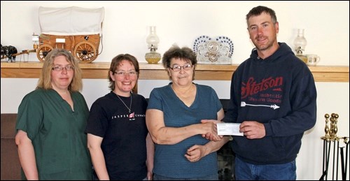 Russell Aumack, president of Rabbit Lake and District Ag Association, presents $5,000 to Lorraine Youst, operator of Rose Gill Lodge and Nicole McNabb and Crystal Wright of the Residents' Fund Committee.