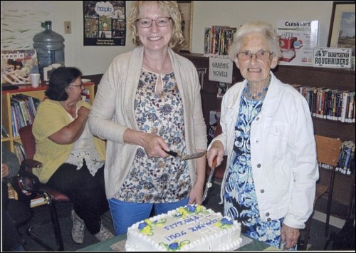 Phyllis Cunningham and Diane Jones cut the cake served at a celebration in honour of Cunningham’s long service to the Speers Library.