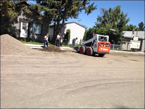 A construction crew of Art Jones, Eric Callbeck, Robert Iverson and Terry Shury in the Bobcat work to solve a drainage problem in front of the Do Drop In.