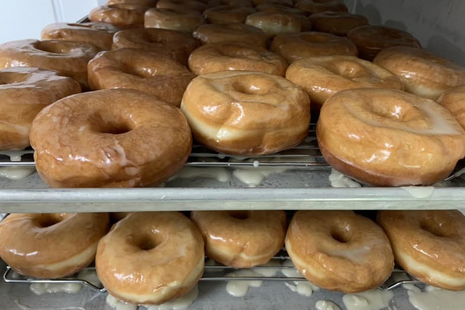 Trays filled with delicious-looking glazed donuts, glistening with icing, at a small bakery in Alberta. / Tina's Cafe & Bakery | Facebook