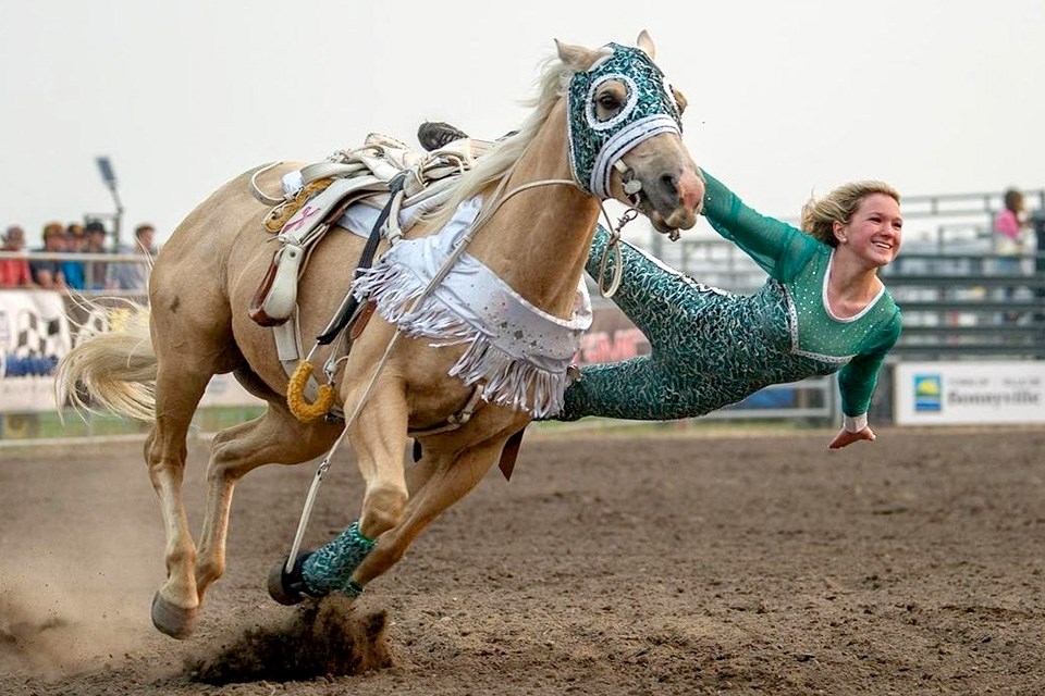 A woman in a sparkly custom gracefully suspended off the side of a horse in movement at the Pincher Creek Pro Rodeo in Alberta. / Pincher Creek Pro Rodeo