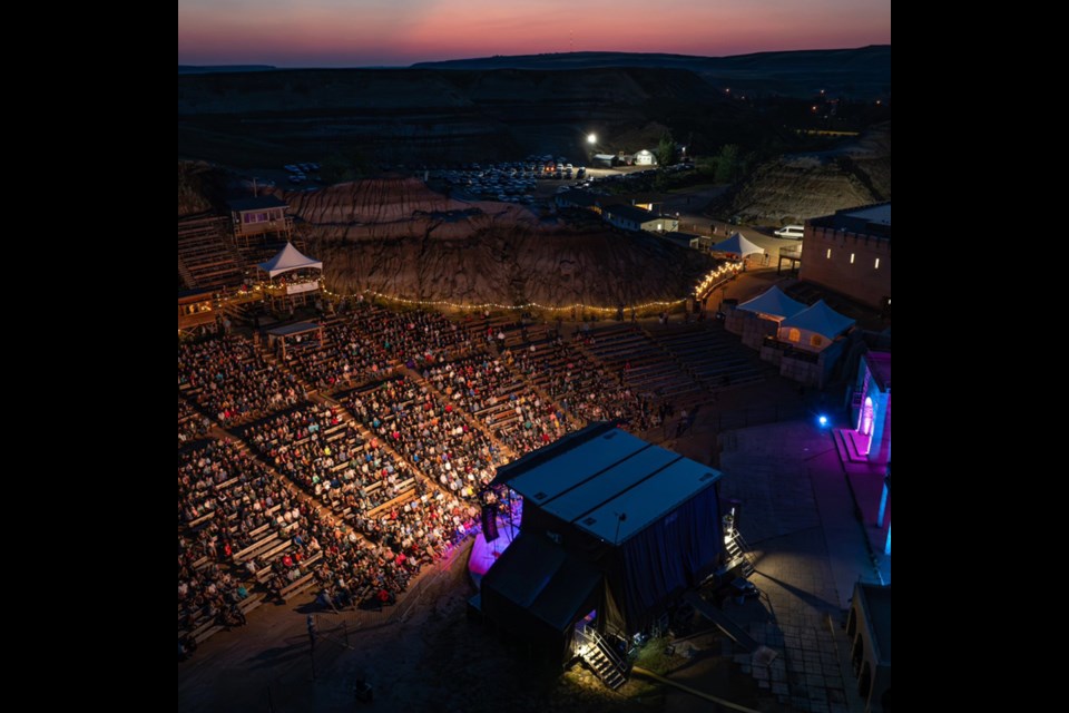 Alberta’s Badlands Ampethetre at night, with stage lights illuminating the crowd and a gorgeous sunset in the background. / Badlands Ampethetre | Facebook