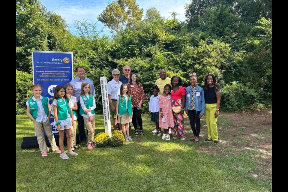 Local Girl Scout Troops and Our Girls Rock, Too are photographed in front of the Statesboro Peace Pole with Mayor Jonathan McColllar. 