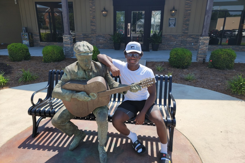 Ja'Kori sitting beside statue of Blind Willie McTell at Visit Statesboro