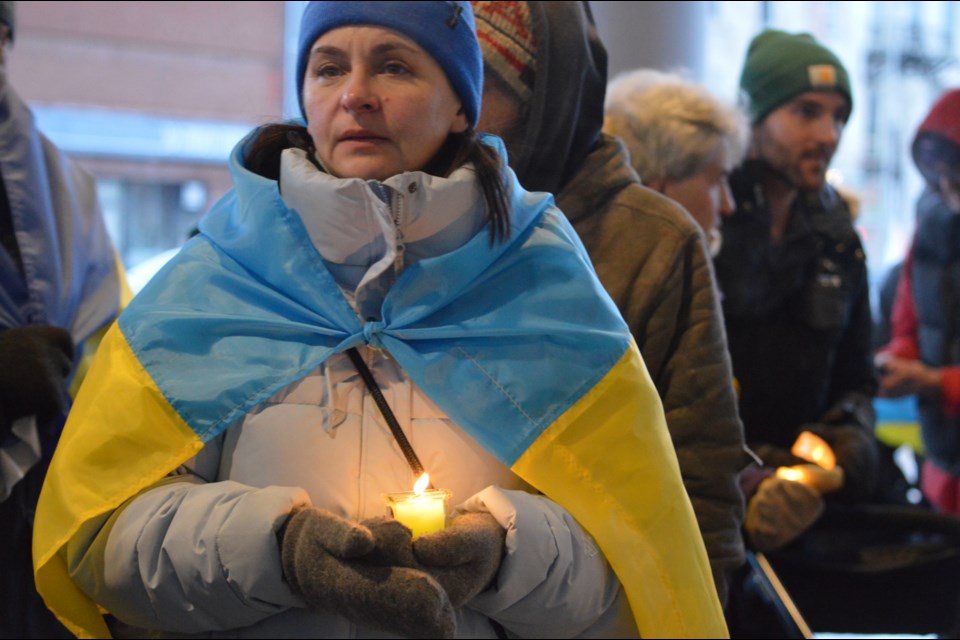 A woman wearing the Ukrainian flag, holding a candle.