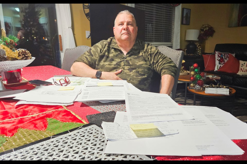 Juan Monterroza sits with the file of documents he's gathered related to an investment property tenant whom he alleges hasn't paid rent in more than a year. File photo