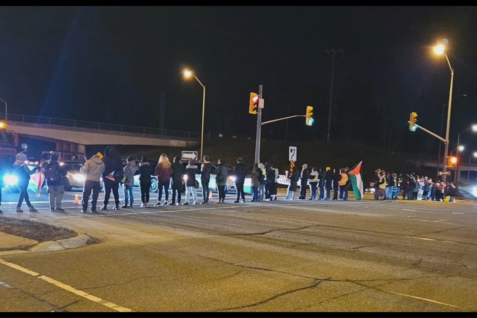 Protestors stand in a line at the Hanlon Expressway and Paisley Street intersection.