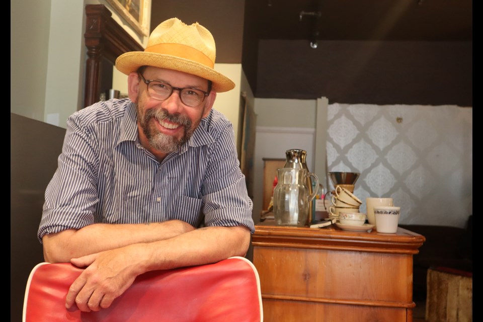 Matthew Forbes leaning on a barber chair at his new business La Poche on 40 Quebec St.