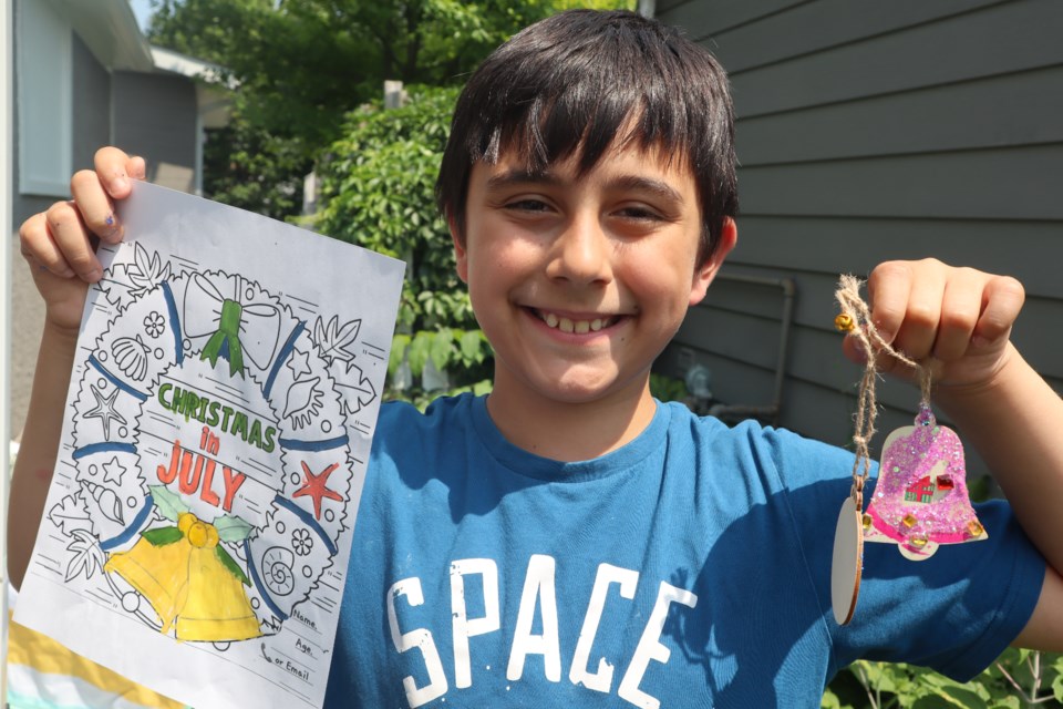 William holds up the crafts he made at Rockwood's Christmas in July on Saturday. The three days of festivities included sidewalk sales, a Christmas-themed farmers’ market, decorations and live music.