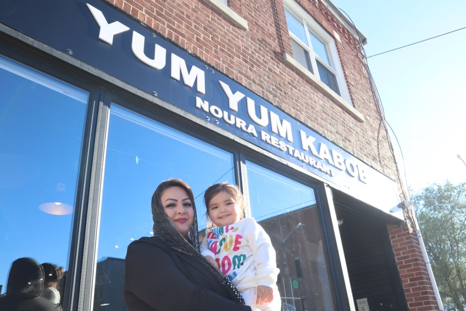 Somya Mohammadi holding her daughter Noura in front of the family's new restaurant, Yum Yum Kabob, in Guelph at 43 Cork St.