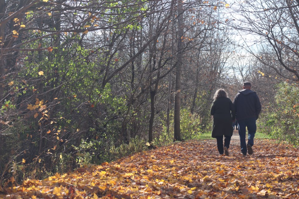 A couple walking on the fallen leaves along the Trestle Bridge Trail in Aboyne.