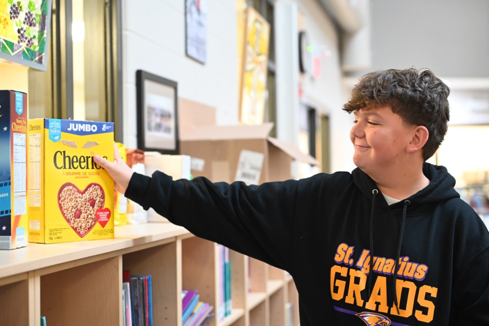 Grade 8 student from St. Ignatius of Loyola Catholic School putting a box of cereal on the shelf.