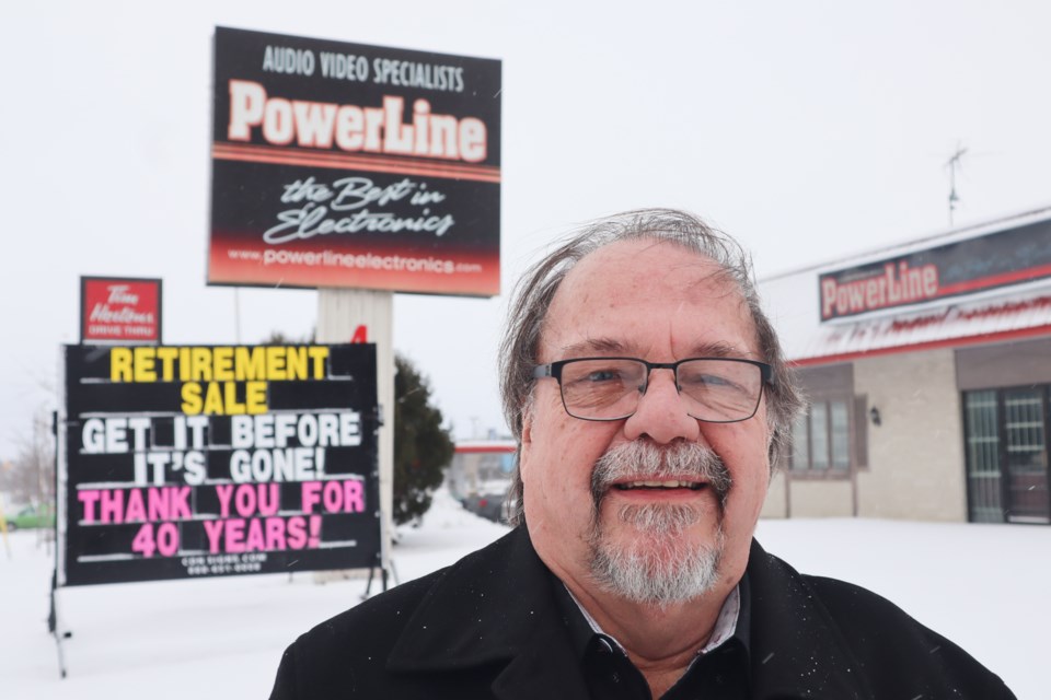 PowerLine Electronics co-owner, Tim Huck, outside the store with its farewell sign.