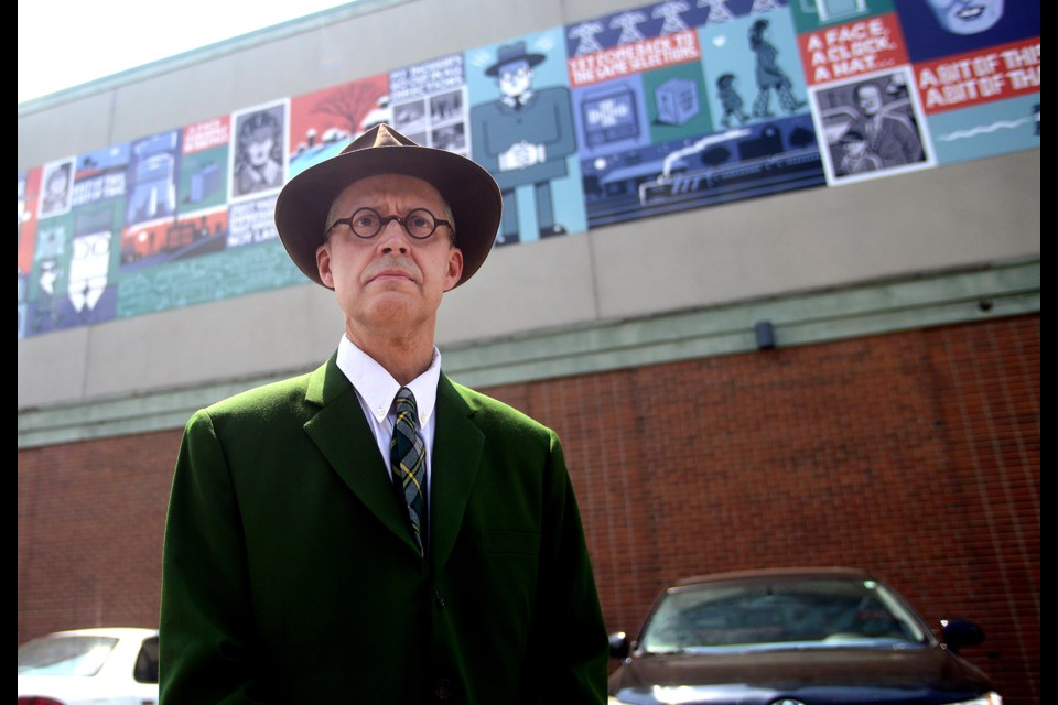 Guelph illustrator Seth poses in front of his work on the side of the Bookshelf in downtown Guelph Saturday, May 28, 2016. Tony Saxon/GuelphToday