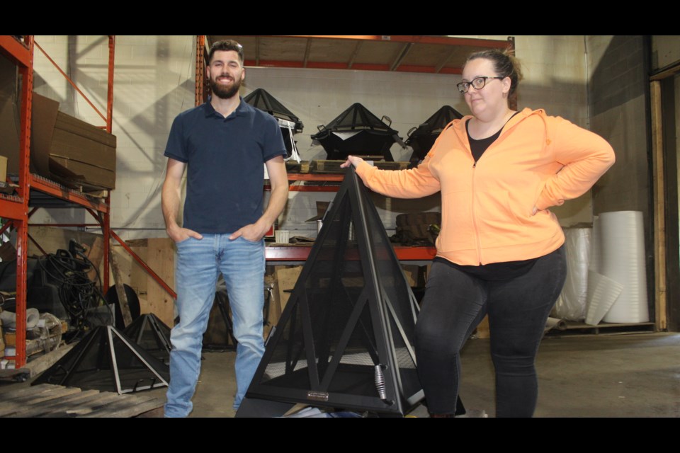 Iron Embers owner and founder Eric Tamminga and administration manager Erica Moore stand beside  a completed pyramid fireplace.