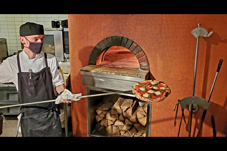 Luke Reist, senior sous chef, removing the pizza from the oven.