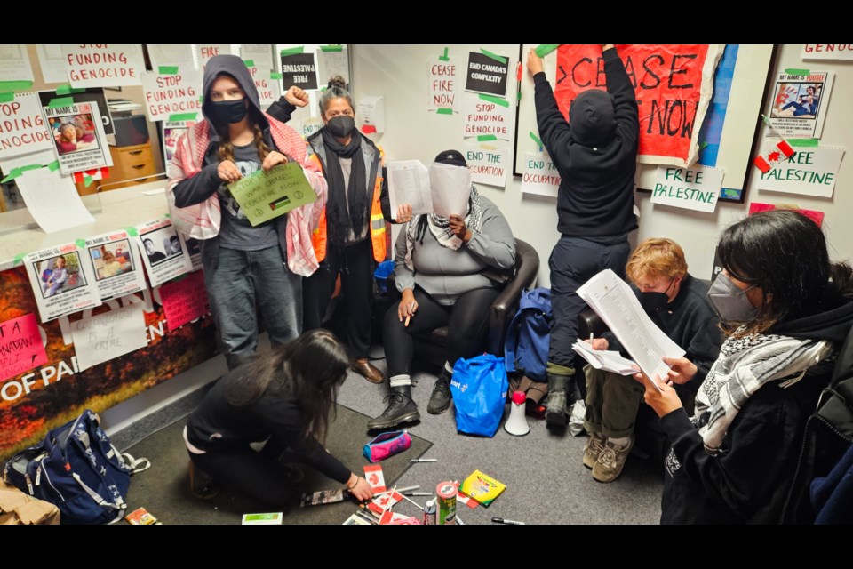 Inside MP Lloyd Longfield's office, about 10 protesters put up signs and read aloud the names of dead Palestinians.