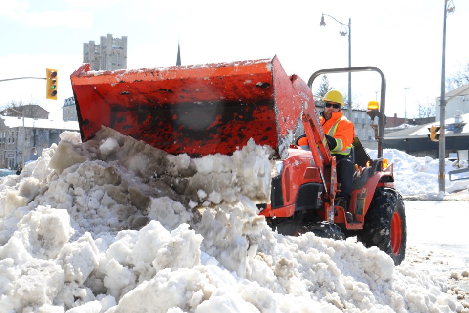 A worker clears snow from the roads and sidewalks downtown. 