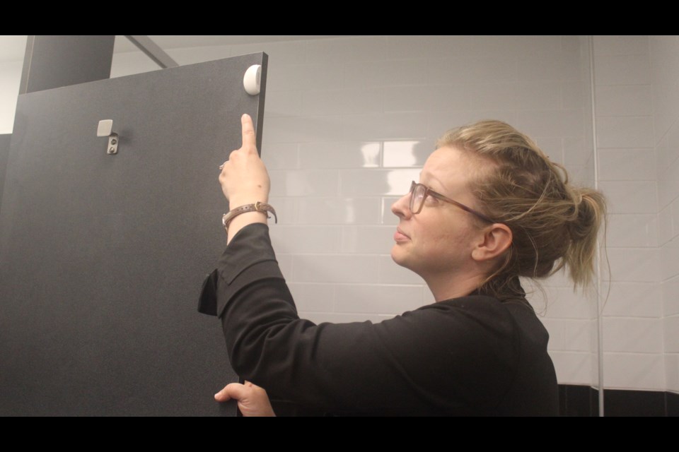 Samantha Wellhauser-Bells, the supervisor of Guelph Public Library's main branch, points to a BRAVE sensor installed on a bathroom stall door.