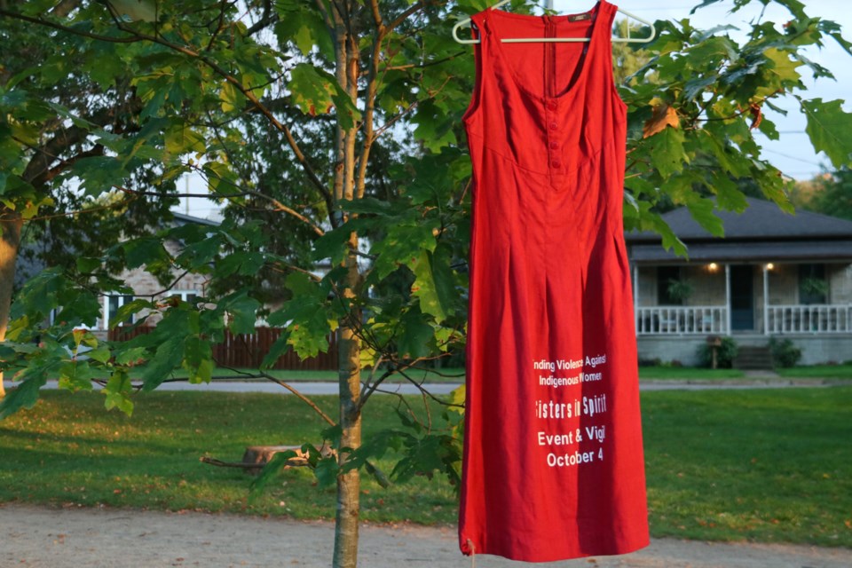 Around 40 red dresses lined the path through Riverside Park as part of Sisters in Spirit, a vigil honouring missing and murdered Indigenous woman, held Friday night.