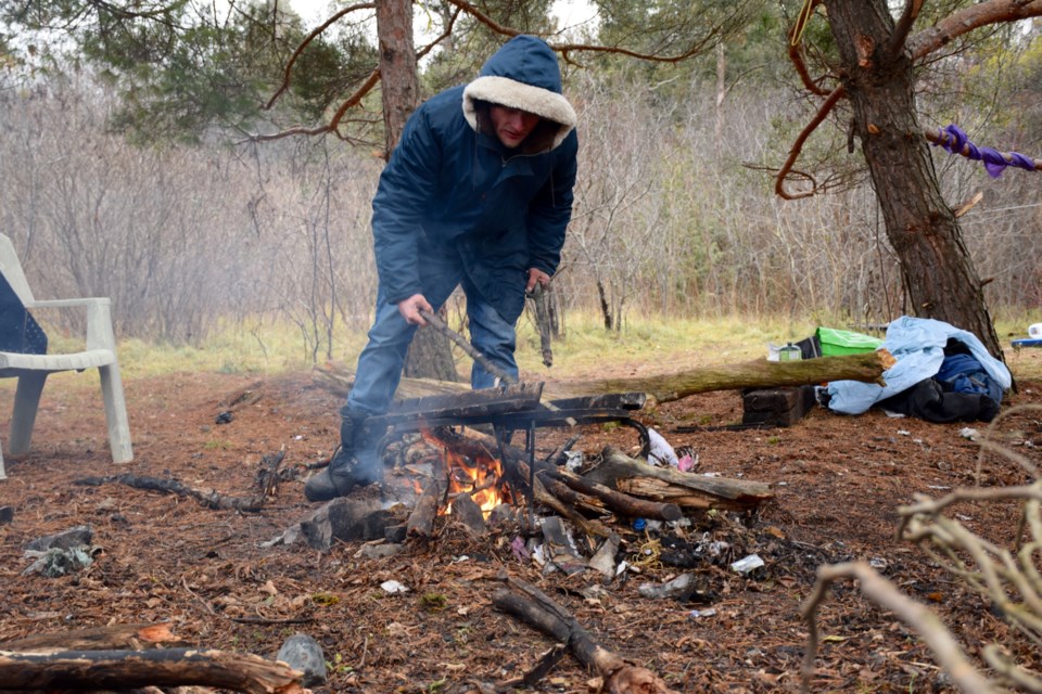 Bobhe Quinn builds a Thursday morning fire at the site of a squatters encampment near the Eramosa River on Guelph's east side. Rob O'Flanagan/GuelphToday