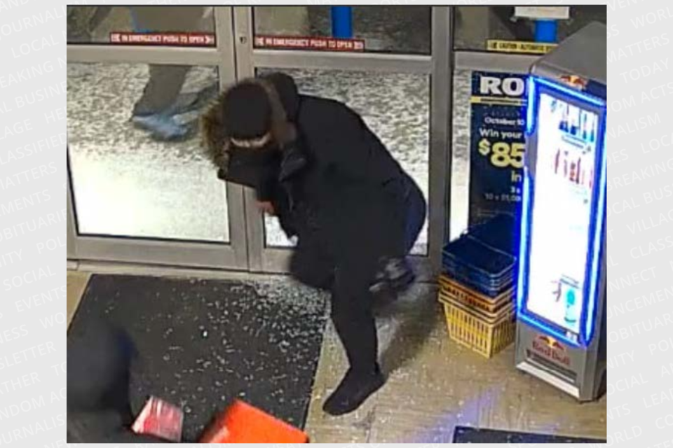 One of the suspects involved in the Rona theft is seen walking through the shattered glass panel.