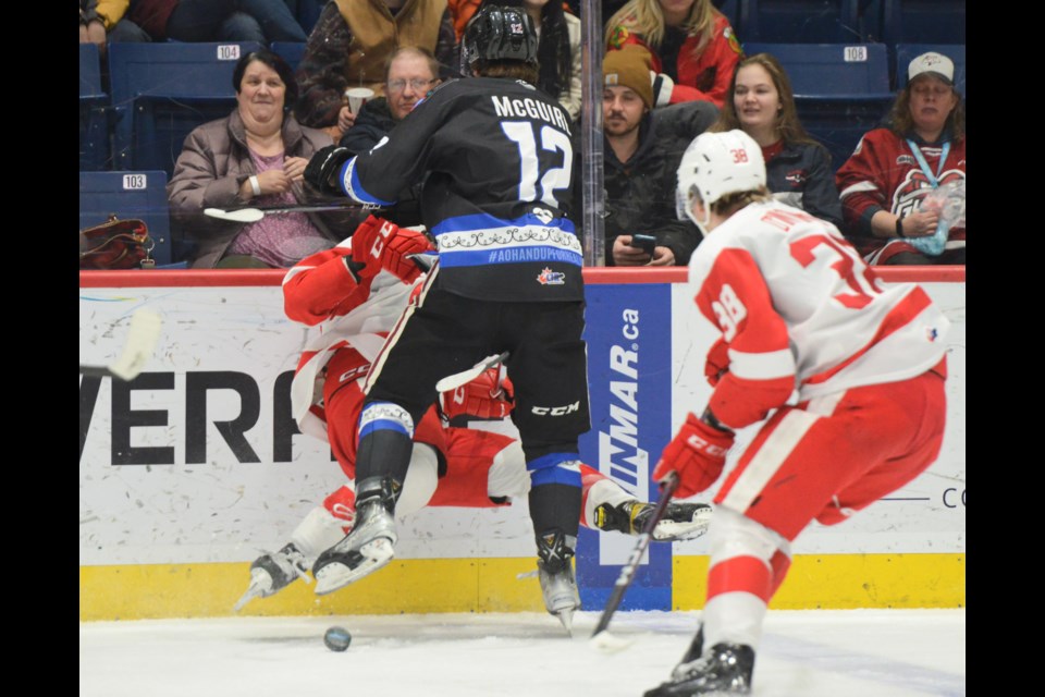 Guelph's Ryan McGuire checks a Soo Greyhounds player into the boards.