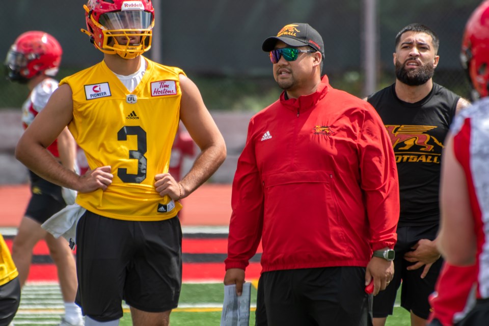 Guelph Gryphons head football coach Mark Surya (red jacket) watches action during the team's training camp at Alumni Stadium alongside quarterback Tristan Aboud. The Gryphons are to open their regular season there Saturday when they're to host the Carleton Ravens.