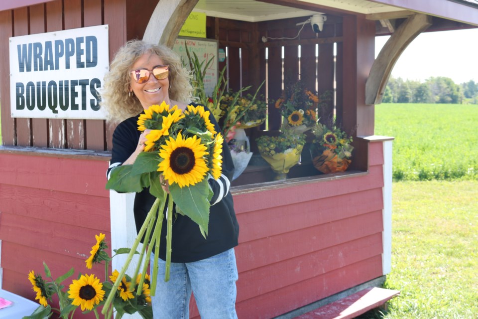 A passerby purchases sunflowers at Raring to Grow's farm stand at 9093 Highway 6 in Kenilworth. Bouquets and beverages are also available. 