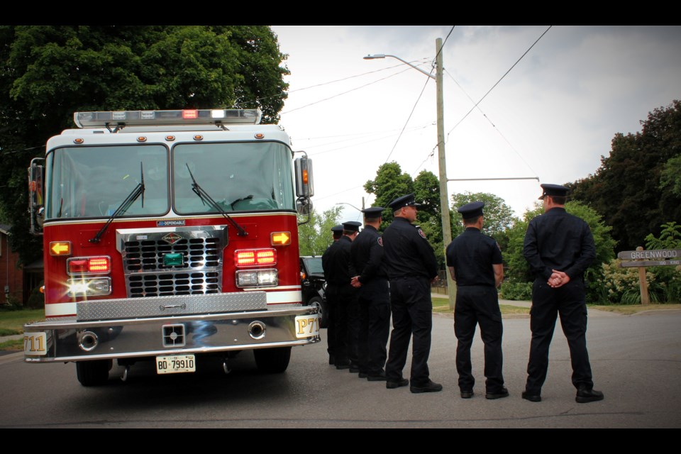 Halton Hills firefighters pay their respects to Bruce Lewis after leading a procession to the cemetery Friday afternoon.