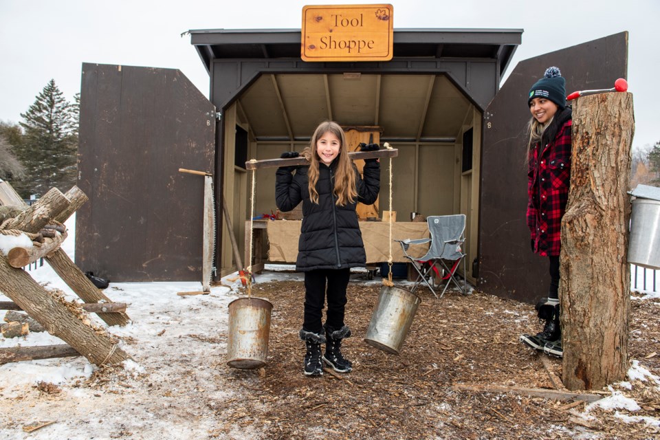 Maya tries out the yoke, which was used to transport maple sap buckets, at Terra Cotta Conservation Area's Maple Syrup in the Park.