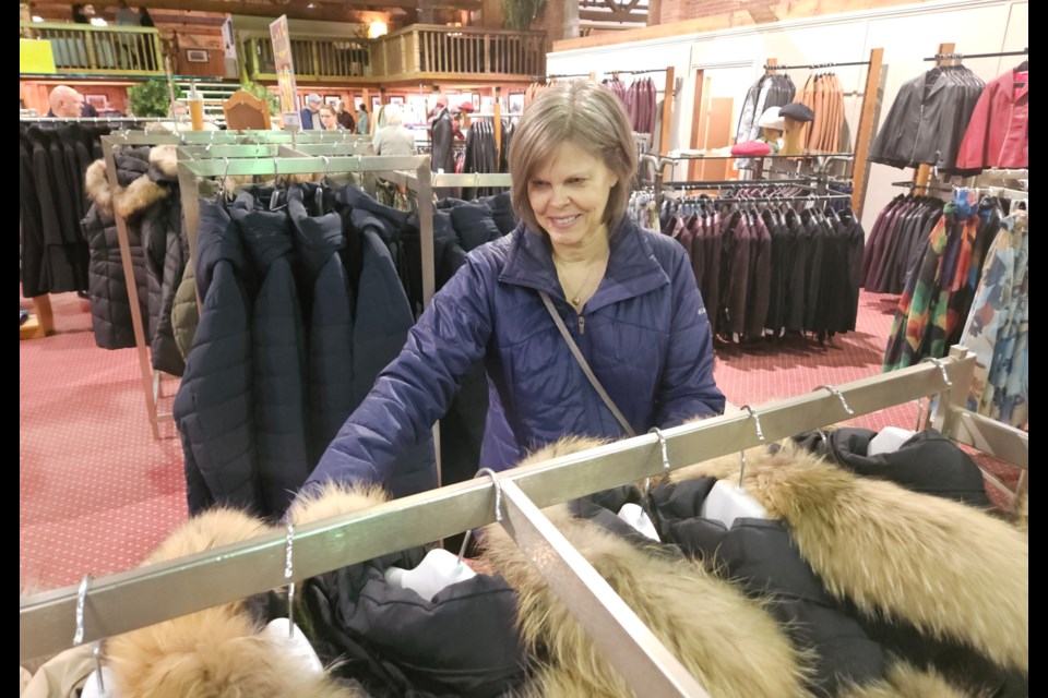 Barb Carscadden, who has been shopping at The Hide House for 30 years, looks through coats at the store Friday morning. The store is liquidating its inventory before closing.