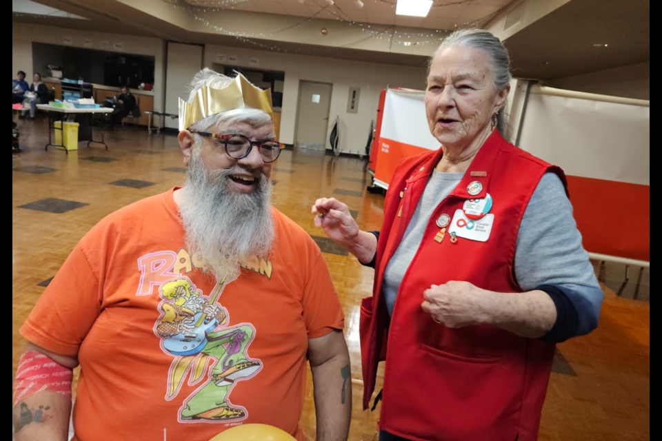 Canadian Blood Services volunteer Fran Morris fits Lar DeSouza with a gold crown after his 100th blood donation Thursday.