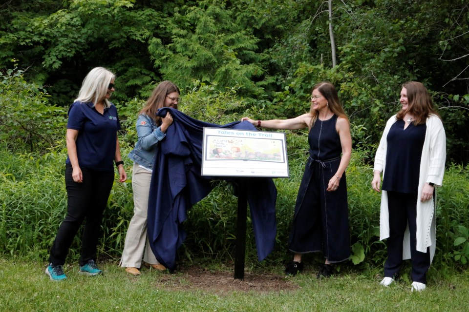 Officials unveil a StoryWalk panel.