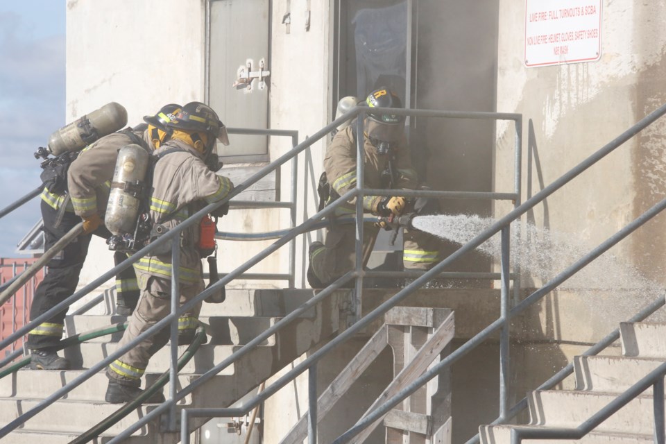 As it will be pitch dark inside the building, firefighters prepare their hoses before entering.  