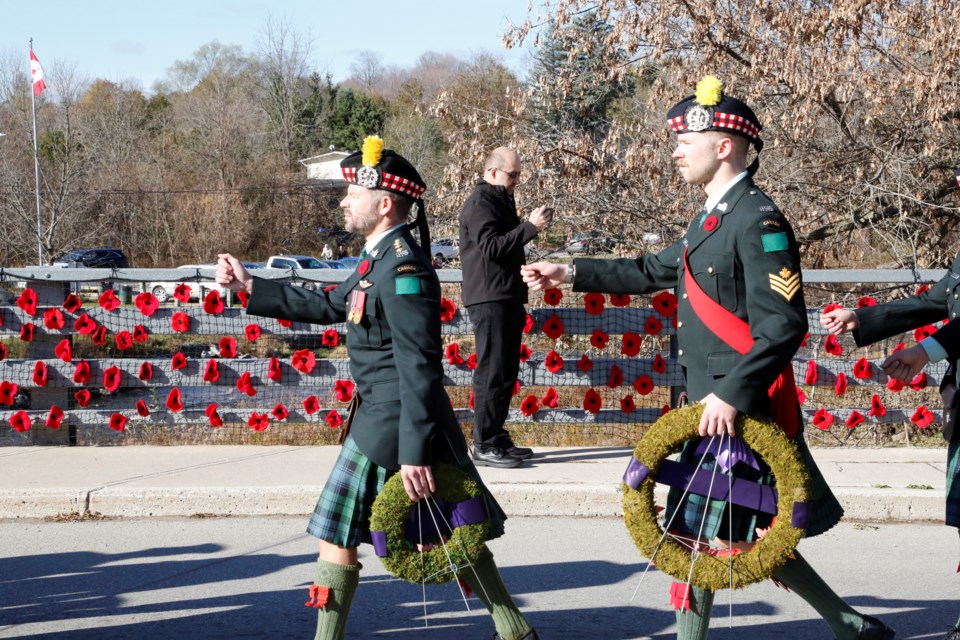 Lorne Scots march past knitted poppies on the Main Street bridge in Glen Williams.