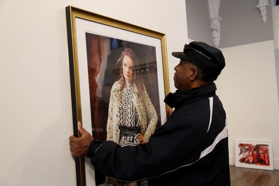 Jamaican-born artist Neville Clarke hangs one of his works at the Helson.