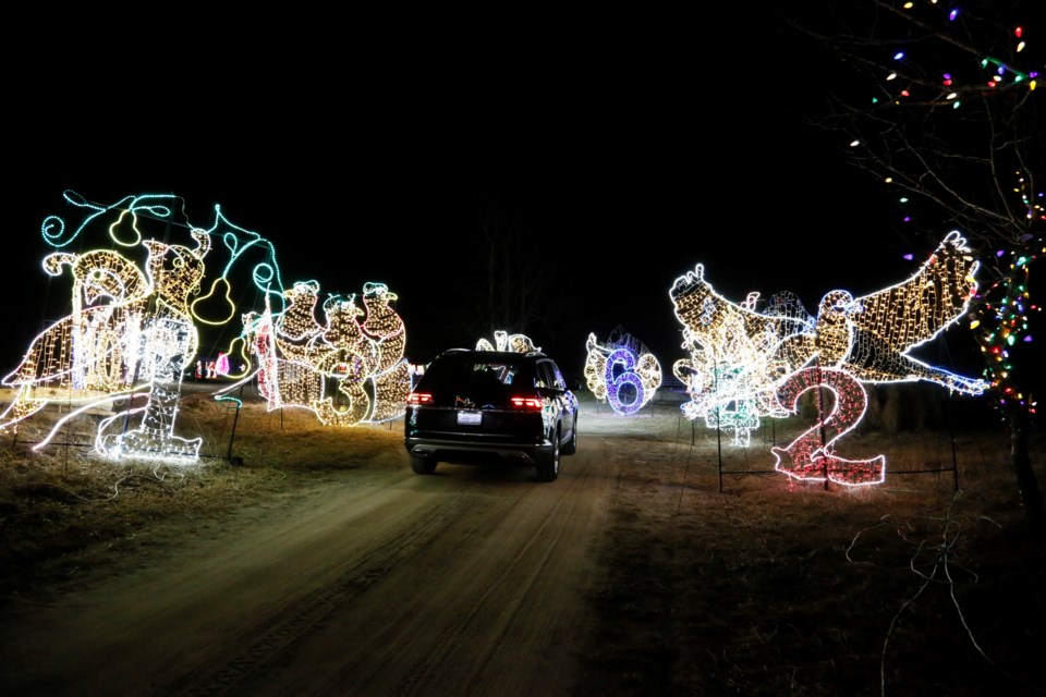 A car drives through a set of lights depicting the 12 days of Christmas.