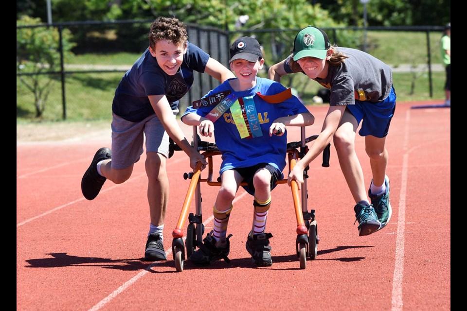 Burlington Central Public School athlete William Lansley, 12, (centre) gets a little help from fellow classmate James Wyborn, left, and Jesse Rewneker in a 100m race at the 37th annual Special Athletics Track Meet.