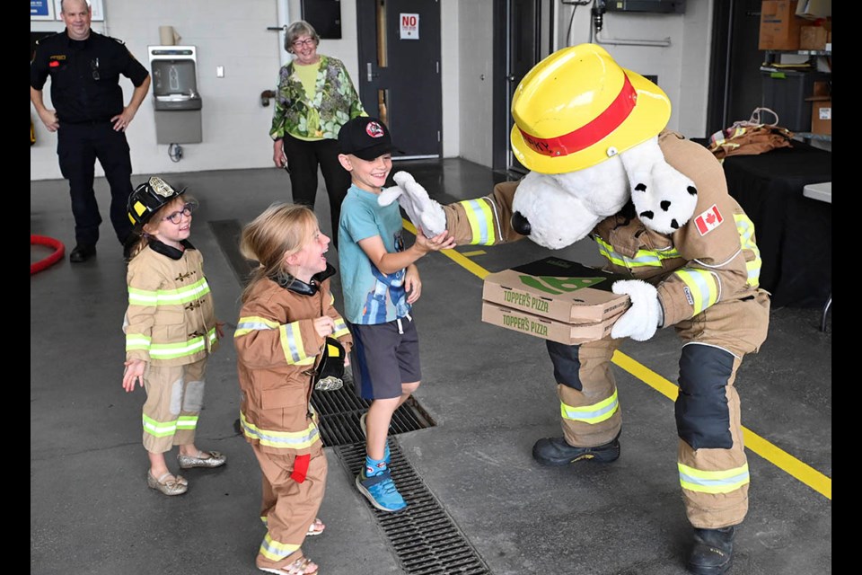 Sparky the fire safety mascot gives a high-five to Isla Greenhill, 5, as her cousin Charlotte Dolson, 5, and her brother Andrew, 8, join in the fun as pizza arrives.