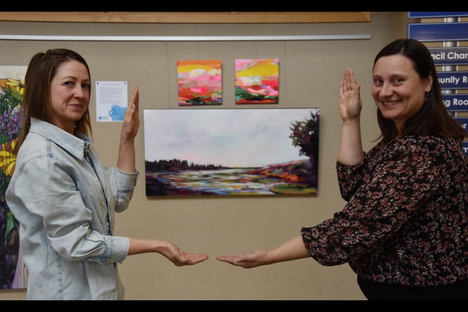 Innisfil library representative Kathryn Schoutsen, right, and Cookstown artist Christine Miller 'frame' some of Miller's art at Innisfil Town Hall recently. Miller's work is currently on display as part of the Art Around the Town initiative. 