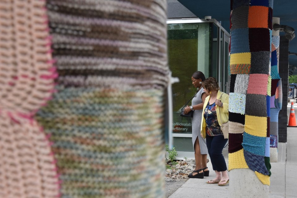 Innisfil councillors Linda Zanella, right, and Grace Constantine stand between yarn-bombed pillars June 5, as they look at the pollinator garden near the main entrance of the Innisfil ideaLAB and Library's Lakeshore branch. 