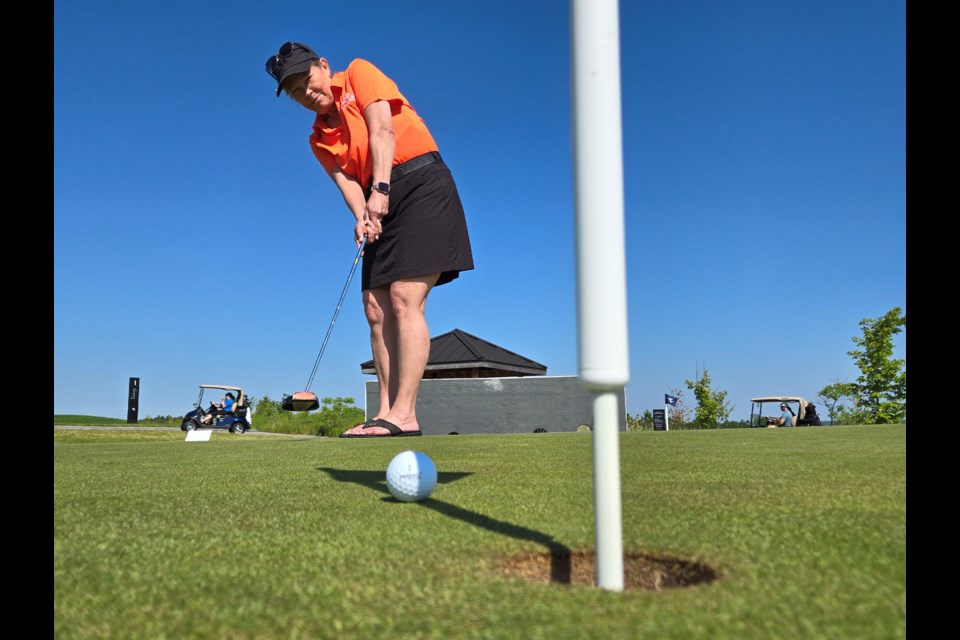 Mayor Lynn Dollin tests out the putting green at The Nest June 17. 