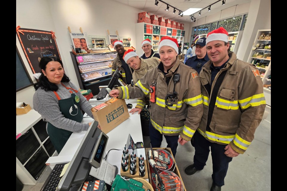 Innisfil firefighters get a bag of items from Body Shop manager Shabana Latifi during the Hometown Holiday Heroes event Dec. 10. 