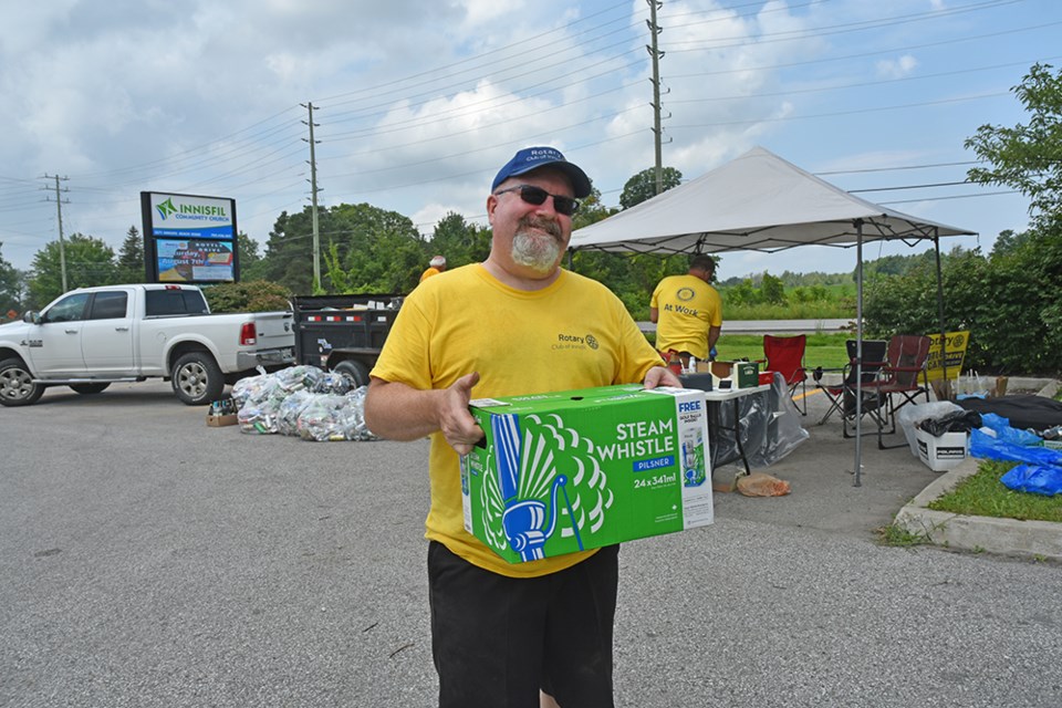 Innisfil Rotary Club president-elect Tim Norton collects 'empties' in the parking lot of Innisfil Community Church.