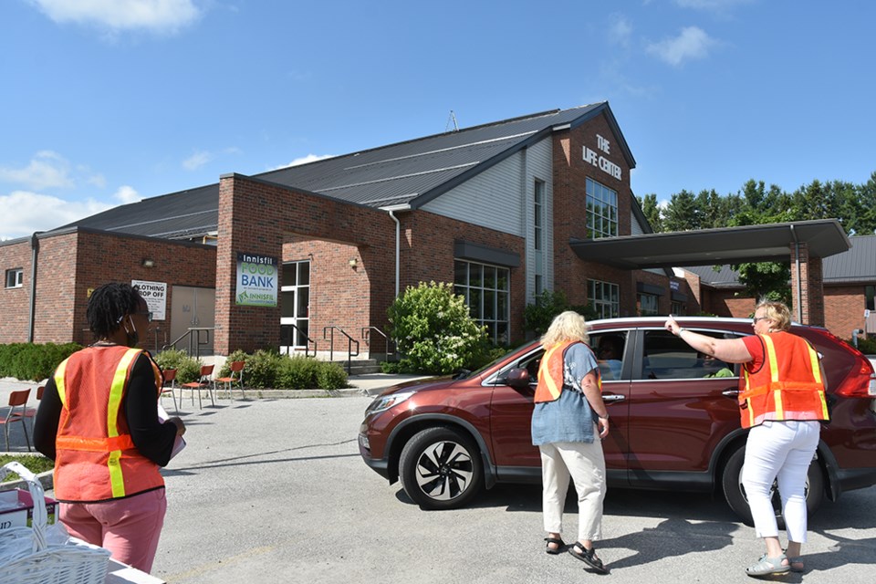 Volunteers direct cars to the field, instead of the parking lot, for an outdoor service at Innisfil Community church.