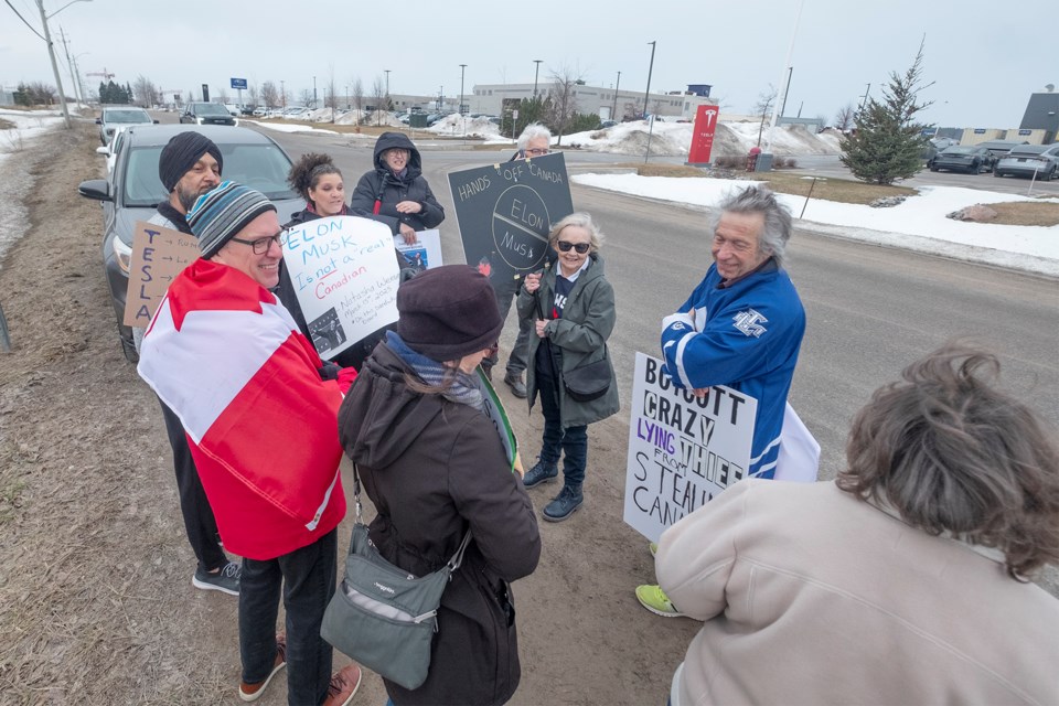 Protesters gather on Doral Drive across from the Tesla dealership in Innisfil on Saturday morning.