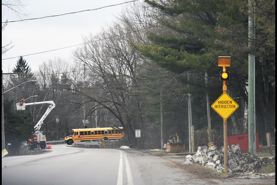 New sign on St. John's Road warns of hidden intersection ahead, while flashing amber light urges caution.